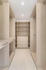Custom closet organization system featuring light wood-finish cabinetry, built-in shelving, integrated drawers with metallic hardware, and recessed li