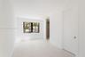 Bright room featuring light wood-finish flooring, a black-framed window, recessed lighting, and built-in closet shelving