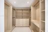 Primary Closet - His Custom wood-finish cabinetry featuring integrated shelving, dual hanging rods, built-in dresser drawers with metallic hardware, a