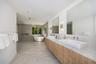 Floating dual vanity with stone-finish countertops, rectangular vessel sinks, wall-mounted faucets, large-format tile flooring, and a freestanding soa