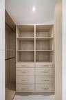 Built-in storage system featuring wood-finish cabinetry, integrated open shelving, double columns of drawers, and metal hardware