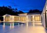 Contemporary exterior featuring smooth stucco finish, expansive stone patio, integrated wall-mounted lighting, multiple sliding glass door sets, and a