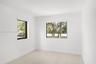 Bright interior space featuring neutral walls, light wood-finish flooring, recessed lighting, and large windows with black frames
