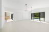 Open living area featuring vaulted ceilings, wood-finish flooring, dual geometric pendant lighting, and multi-panel sliding glass doors with exterior 