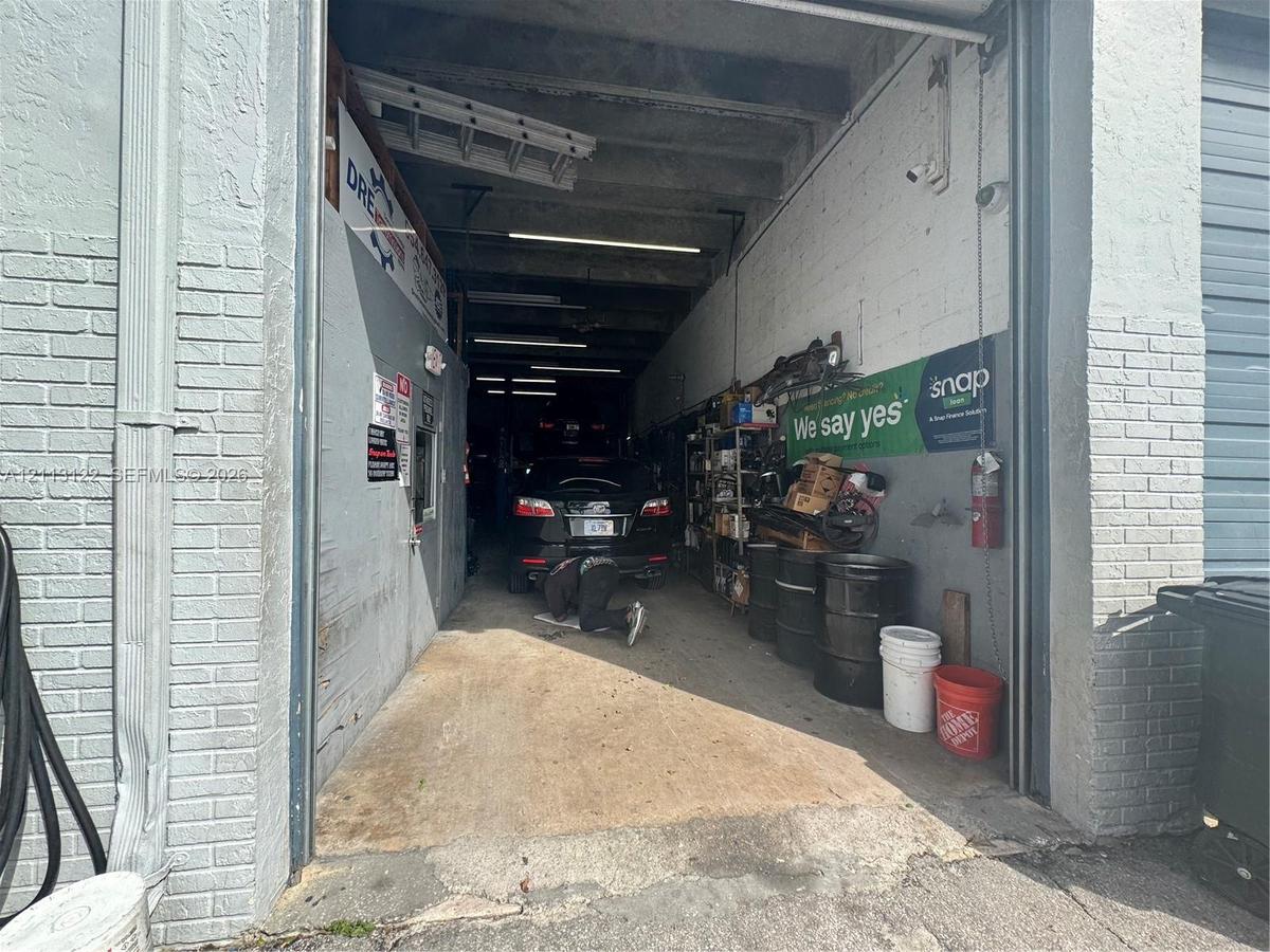 Industrial bay featuring high-clearance overhead door access, painted brick exterior, and open-span interior layout with exposed ceiling structural be