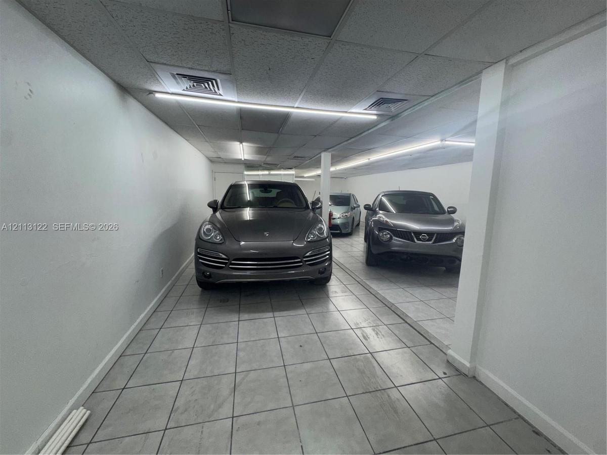 Enclosed parking area featuring tile flooring, smooth wall finishes, and LED linear lighting