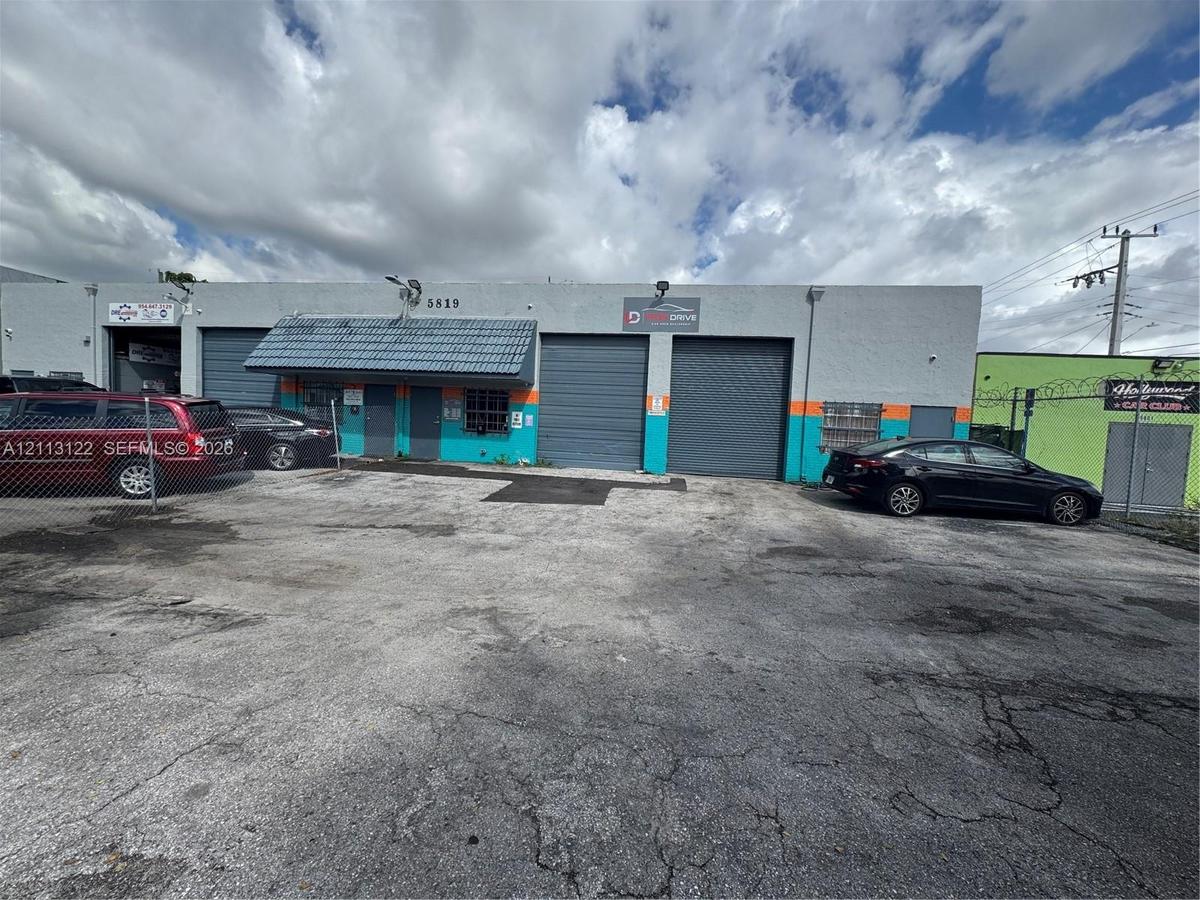 Commercial exterior featuring two metal roll-up doors, a flat roofline, and paved frontage