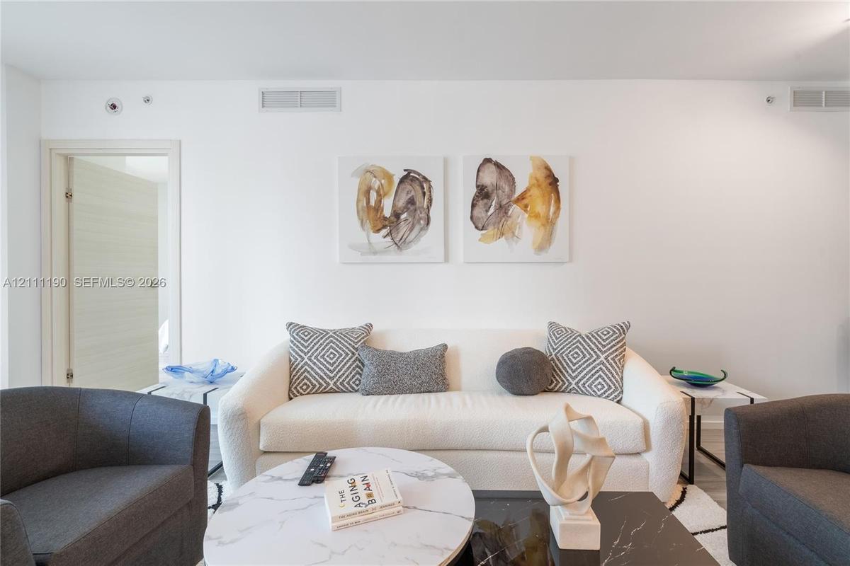 Neutral interior space featuring high ceilings, a flat-panel interior door with brushed metal hardware, and minimalist light-toned wall finishes