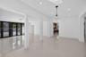 Open-concept interior featuring large-format polished tile flooring, recessed lighting, architectural columns, and dark-framed glass paneled doors