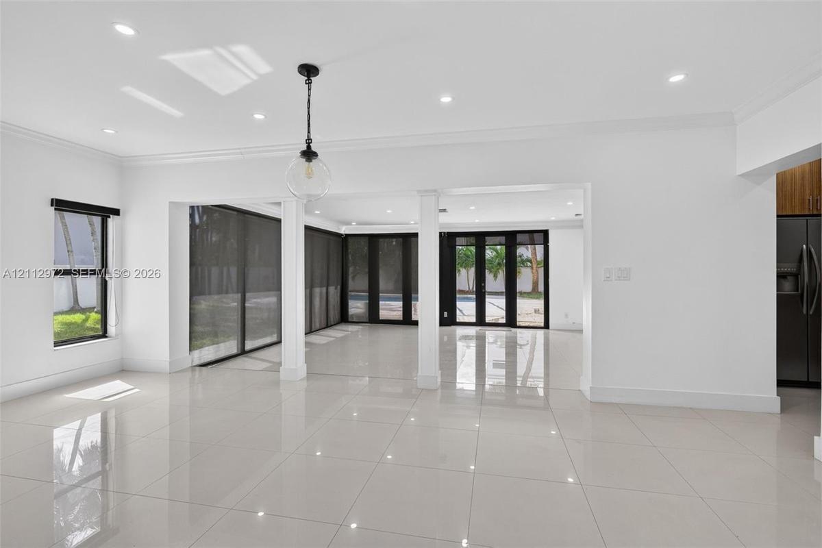 Large-format polished tile flooring, recessed ceiling lighting, structural support columns, black-framed sliding glass doors, and a decorative globe p
