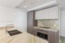Kitchen featuring stone countertops, integrated wood-finish cabinetry, a built-in stainless steel oven, a glass cooktop, and a stainless steel undermo