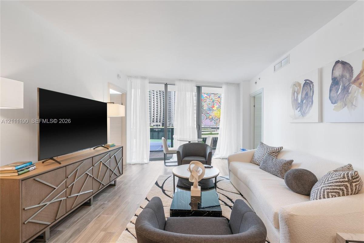 Living area featuring wood-finish flooring, floor-to-ceiling windows, and access to an exterior balcony