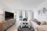 Living area featuring wood-finish flooring, floor-to-ceiling windows, and access to an exterior balcony