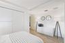 Full-height closet with white panel doors, wood-finish flooring, tray ceiling, and a light wood-finish interior door