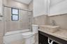Bathroom featuring a custom stone vessel sink with a chrome faucet, solid-surface vanity countertop, glass-enclosed shower with tiled walls, and decor