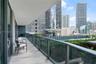 Covered balcony featuring wood-finish flooring, glass panel railings, and full-height sliding glass doors