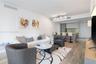 Open-concept interior featuring wood-finish flooring, kitchen with a stone-surface breakfast bar, slab backsplash, multi-tonal cabinetry, and track li
