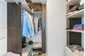 Walk-in closet featuring dark wood-finish cabinetry, built-in shelving, integrated hanging rods, and floor-level storage surfaces