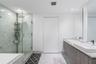 Bathroom featuring a floating vanity with dual rectangular vessel sinks, stone-finish countertops, a glass-enclosed shower with floor-to-ceiling tile,