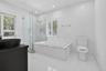 Modern bathroom featuring a glass-enclosed walk-in shower, a deep-soaking bathtub with tile surround, plantation shutters, and a dark-finish vanity wi