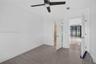 Neutral-toned wood-finish flooring, ceiling fan with integrated light, and solid-core interior doors