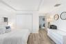 Tray ceiling with recessed lighting, wood-finish flooring, and white bifold closet doors