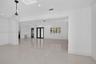 Open-concept interior featuring large-format porcelain tile flooring, crown molding, recessed lighting, double entry doors, and a decorative glass pen
