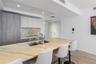 Kitchen featuring an oversized stone-surfaced island with an integrated stainless steel dual-basin sink, high-contrast cabinetry, matching stone backs