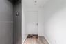 Entryway featuring a white door with metallic lever hardware, dark grey wall paneling, and wood-finish flooring
