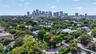 Aerial perspective of a residential lot featuring mature canopy trees, proximity to urban infrastructure, and a skyline backdrop