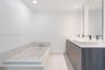 Bathroom featuring a dual-sink vanity with wood-finish cabinetry, white countertop, rectangular vessel sinks, recessed lighting, and a bathtub with st