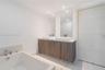 Double vanity with rectangular vessel sinks, quartz countertops, wood-finish cabinetry, chrome fixtures, and a soaking tub