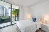 Floor-to-ceiling glass sliding doors, private balcony with metal railing, and wood-finish flooring