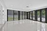 Polished porcelain tile flooring, recessed LED lighting, and expansive floor-to-ceiling black-framed glass wall panels opening to a rear exterior pati