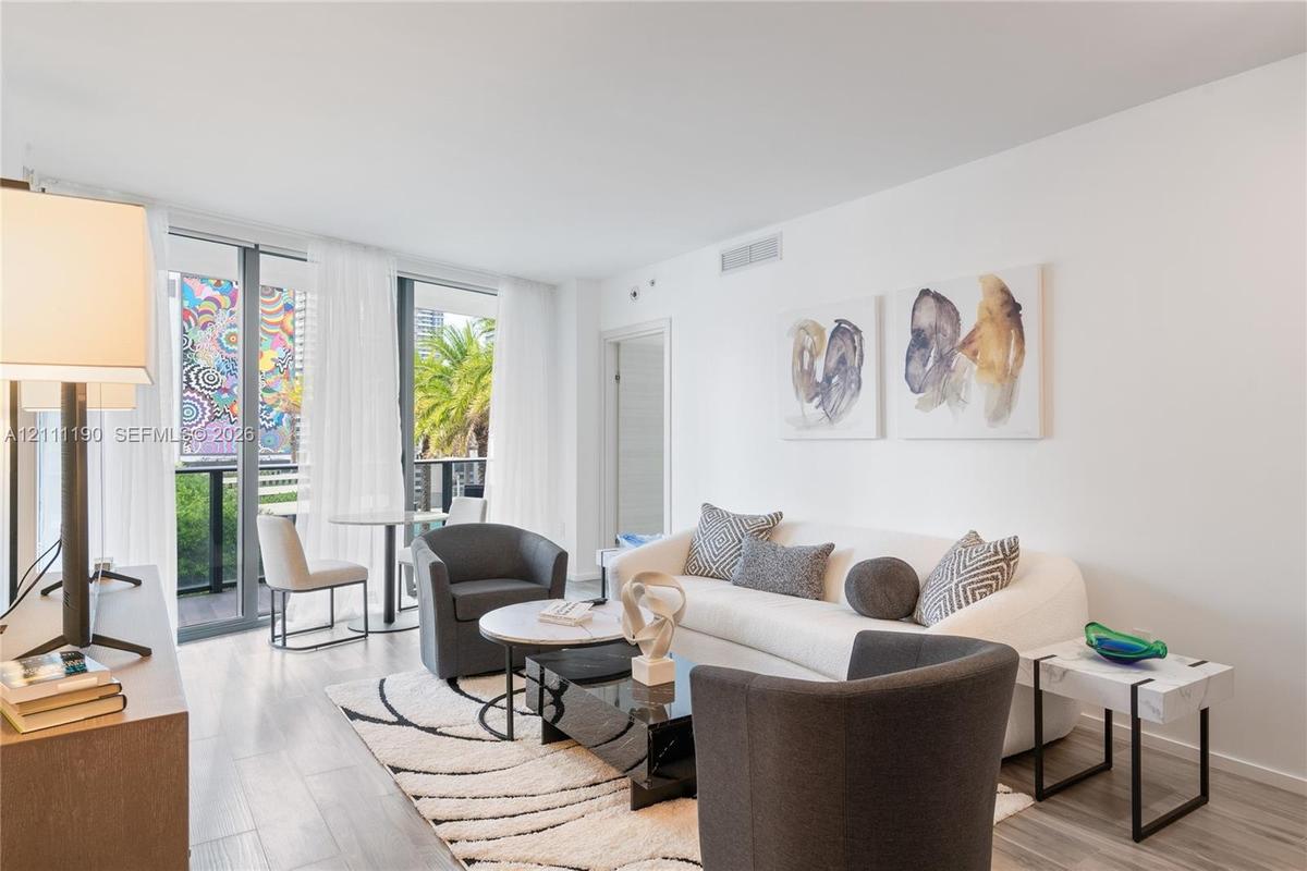 Floor-to-ceiling glass sliding doors, wood-finish flooring, and balcony access