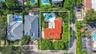 Aerial perspective featuring a terracotta tile roof, private swimming pool, concrete patio, and mature tree canopy on the parcel