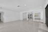 Open-concept interior featuring large-format tile flooring, recessed lighting, crown molding, and structural columns