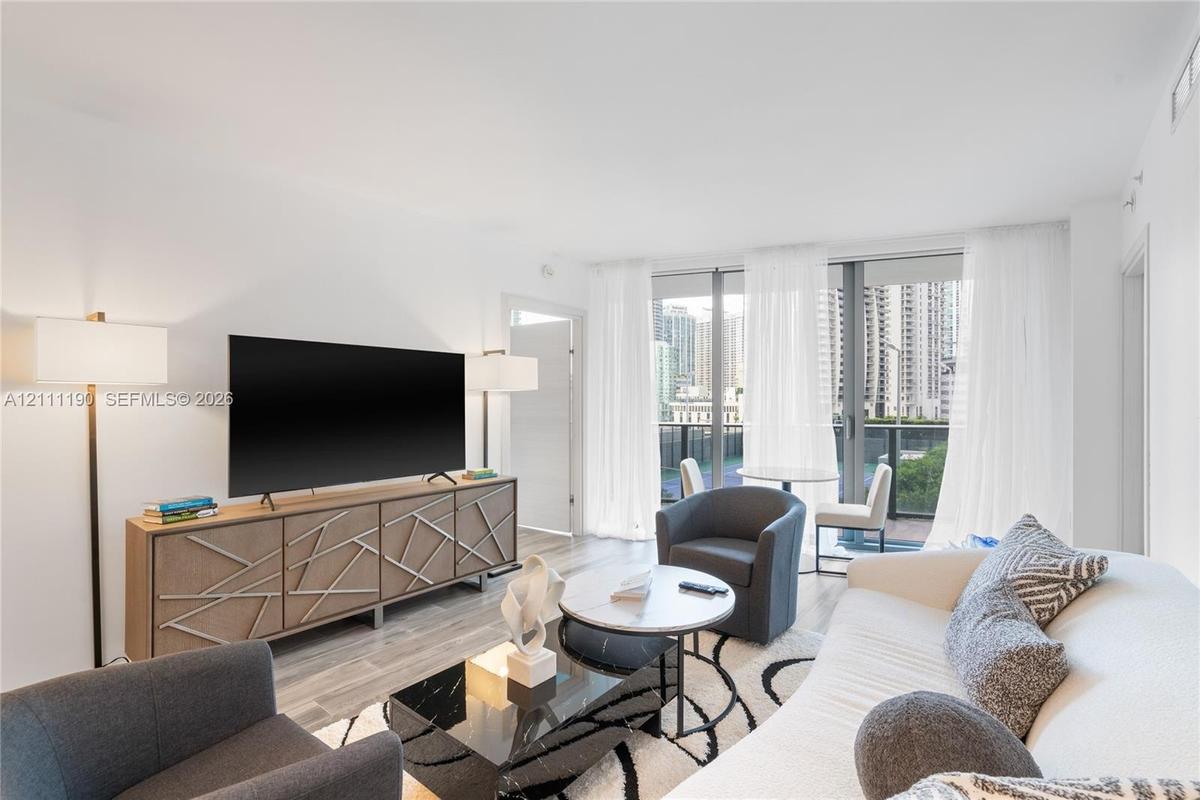 Living space featuring floor-to-ceiling glass sliding doors, wood-finish flooring, and neutral wall tones
