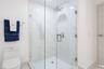 Walk-in shower featuring a frameless glass enclosure, floor-to-ceiling stone-finish tile surround, wall-mounted polished chrome fixtures, and a ceilin