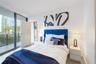 Floor-to-ceiling glass sliding doors, wood-finish flooring, and access to a private balcony