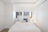 Tray ceiling, horizontal window, and floor-to-ceiling closet with dual-panel doors, featuring wood-finish flooring