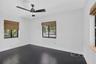 Dark-toned wood-finish flooring, matte black ceiling fan with integrated lighting, and woven bamboo window shades