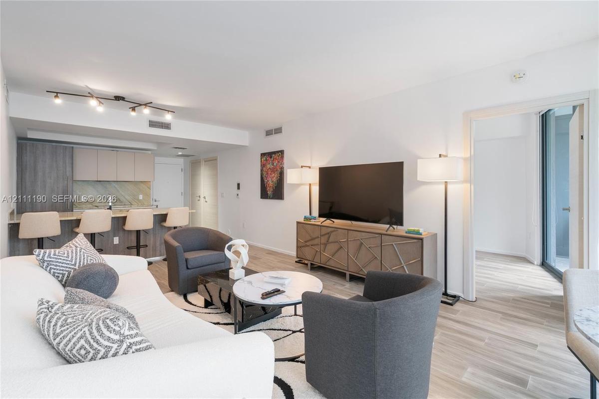 Open concept interior featuring wood-finish flooring, recessed track lighting, and a kitchen peninsula with integrated stone-finish countertop