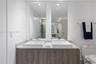 Dual-sink vanity featuring textured wood-finish cabinetry, a stone countertop, two rectangular vessel sinks, and wall-mounted vertical mirrors