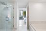 Glass-enclosed shower with a rainfall showerhead, stone-finish tile surround, built-in soaking tub, and stone flooring