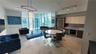 Open-concept living space featuring floor-to-ceiling windows, large-format tile flooring, modern kitchen cabinetry with built-in appliances, and desig