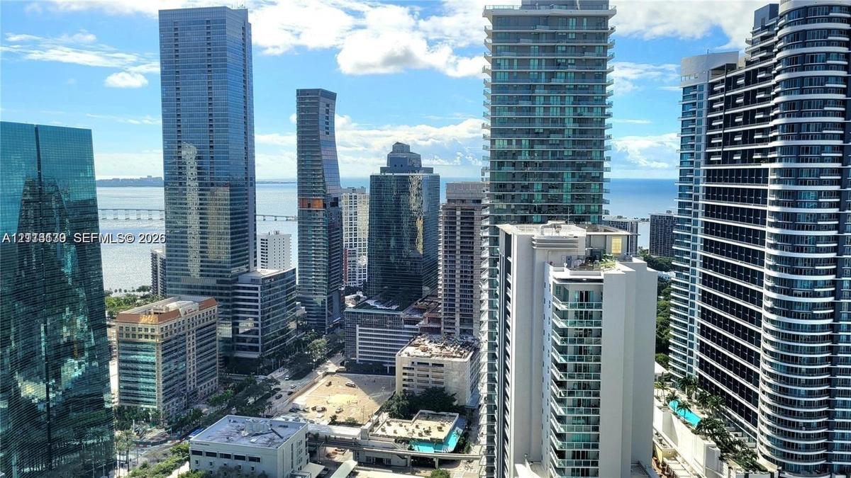 High-rise urban panorama featuring glass-facade skyscrapers, bay water, and distant bridge infrastructure