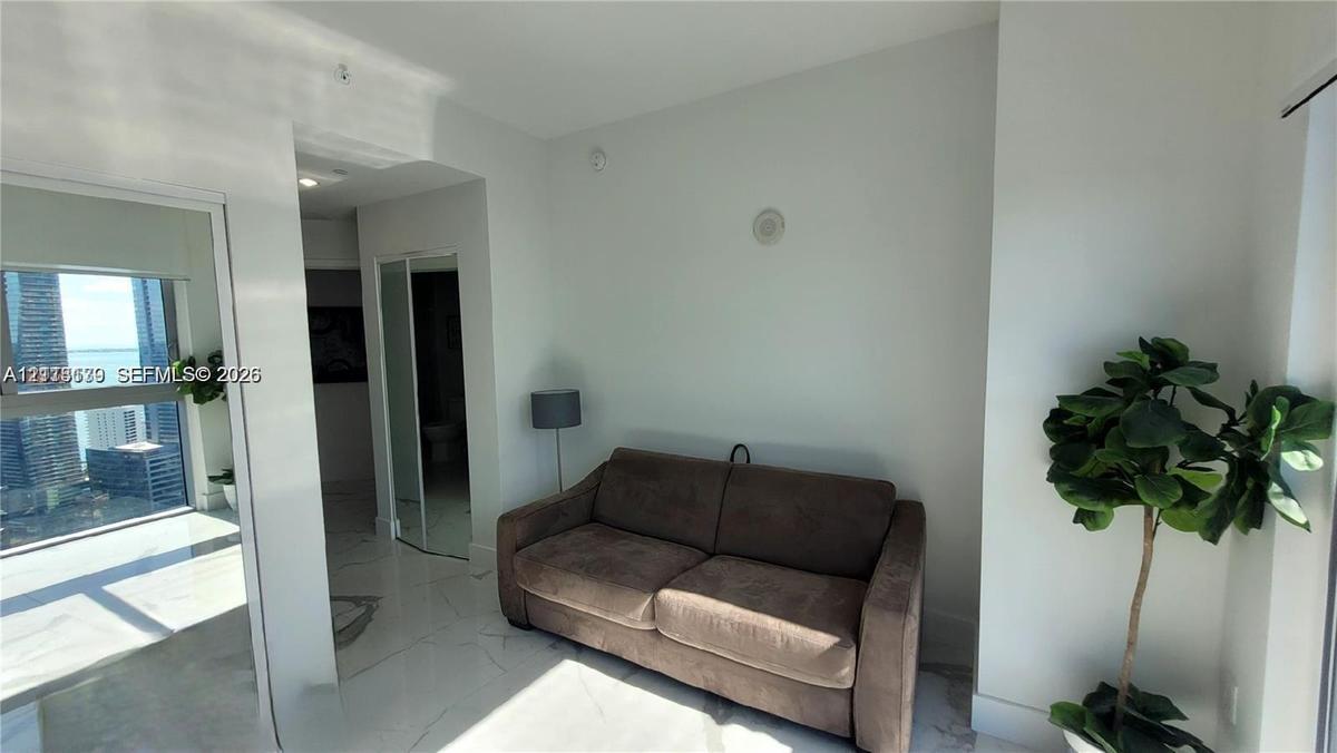 Interior space featuring polished stone-finish flooring, floor-to-ceiling glass paneling, and mirrored closet doors