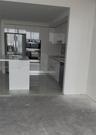 Kitchen featuring high-gloss cabinetry, stone-surface countertops, an integrated island, built-in stainless steel appliances, and tile flooring