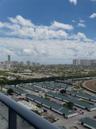 Elevated balcony railing with a panoramic outlook featuring city high-rises, expansive horizon, and racetrack grounds